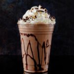 Chocolate milkshake served in a clear glass on a dark background. Isolated drink.